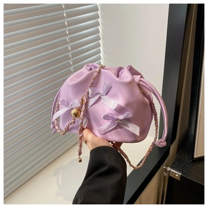 Detail einer lavendelfarbenen Beuteltasche mit Satinschleife und Goldkettenriemen