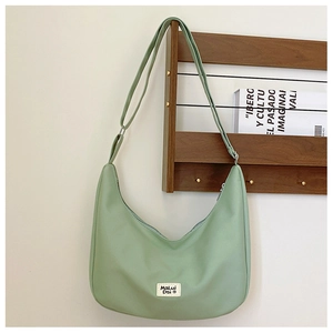 Detail view of a light green nylon saddle bag hanging on a minimalist wooden wall rack
