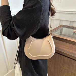 Chic beige leather shoulder bag with unique U-shaped piping design on simple background