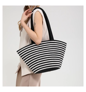 Détail d'un sac cabas tissé à rayures noires et blanches avec de longues anses noires