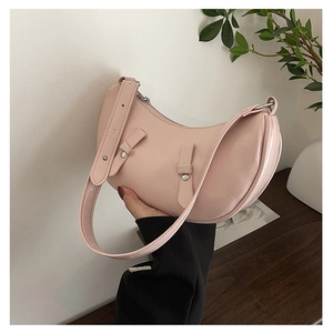 Detailed shot of pink crescent shoulder bag with wide strap and silver buckle accents