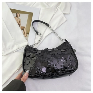 Macro detail of glossy black sequins and silver chain strap on a trendy hobo bag