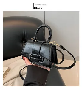 Detail of a black pleated leather mini handbag with gold hardware and top handle