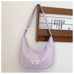 Detailed shot of lavender nylon saddle bag featuring branded woven label and adjustable strap