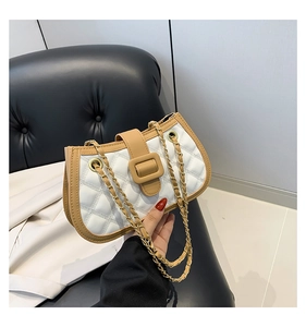 Detail of white quilted crossbody bag with caramel leather trim and gold chain strap