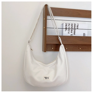Detail of white nylon saddle bag with adjustable strap and brand label on wooden wall
