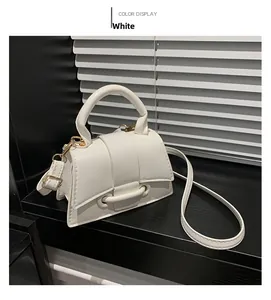 Detail of white PU leather crossbody bag with golden hardware and round top handle