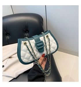 Detail of white quilted crossbody bag with dark green trim and golden chain strap