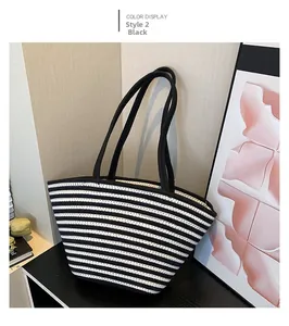 Détail d'un grand sac cabas en paille à rayures avec des anses en toile noire sur bois