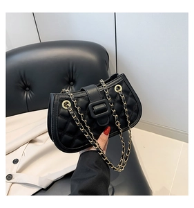Detail of black quilted leather shoulder bag with gold chain strap and buckle