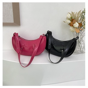 Detail of trendy crescent underarm bags in fuchsia and black with wide shoulder straps