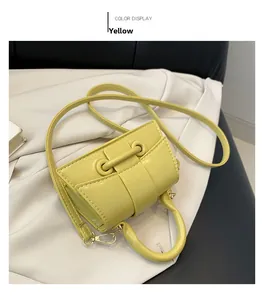 Detail of a bright yellow mini handbag with metal buckle and textured PU leather