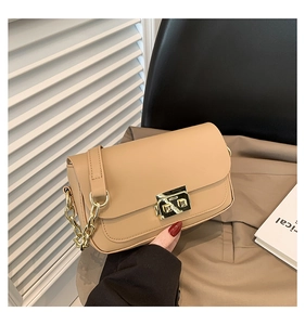 Detail of apricot flap bag with golden twist lock and thick chain on a blazer