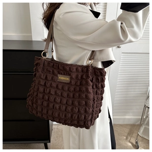 Détail du sac cabas marron foncé avec texture bulle et anneaux métalliques dorés