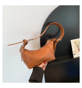 Macro shot of caramel brown faux leather underarm bag featuring silver metal buckle details