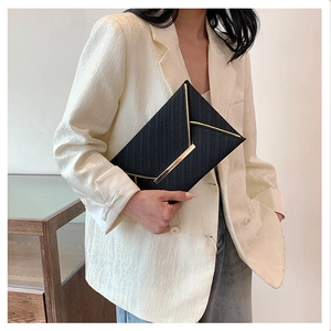 Détail de la pochette enveloppe noire avec texture tissée et bordure dorée élégante