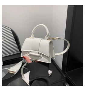 Close-up of white mini handbag with textured synthetic leather and gold hardware