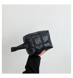 Detail of black quilted tote bag showing padded fabric texture and puffy handle design