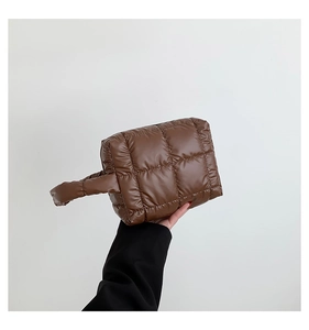 Detail of deep brown quilted nylon puffer tote bag with soft padded texture and top handles