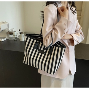 Detail of black and white striped canvas tote with premium leather straps on shoulder