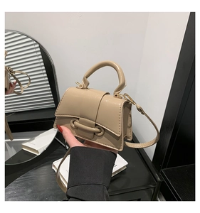 Detailed close-up of beige PU leather mini bag with U-shaped metallic buckle detail