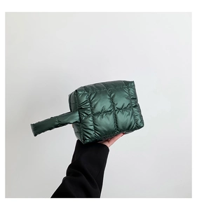 Detail of dark green quilted padded handbag with glossy finish and soft fabric texture