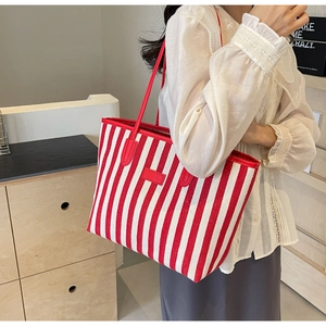 Close-up of red striped canvas tote bag with premium leather shoulder straps detail
