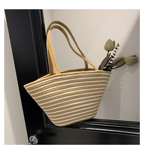 Détail d'un grand sac cabas en paille rayé avec poignées tressées et motifs kaki