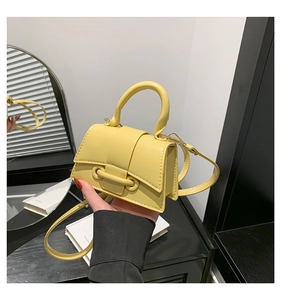 Detail of yellow minimalist handbag with top handle and adjustable shoulder strap
