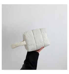 Close-up of a white quilted puffy handbag featuring classic square stitched patterns
