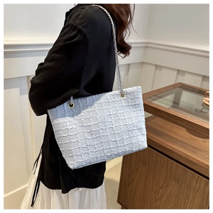 Detail of light blue woven plaid tote bag with elegant gold metal buckle and chain strap