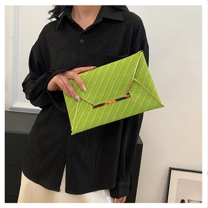 Détail de la pochette enveloppe verte avec texture tissée et bords dorés fins