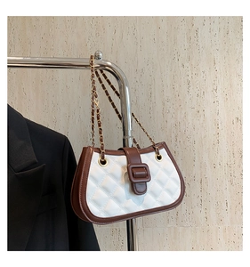 Detailed view of white quilted crossbody bag with brown trim and gold chain strap