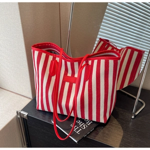 Detail of red and white striped canvas tote bag with slim handles in a natural light setting
