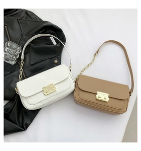 Detail view of leather underarm bags with gold metal clasps and chain straps in two colors