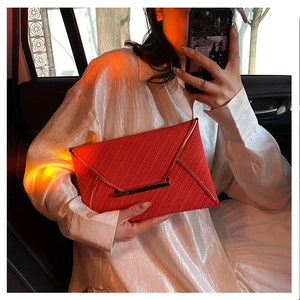 Pochette enveloppe rouge avec texture tressée et bordure dorée dans une voiture