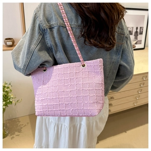 Pink tweed tote bag featuring gold chain strap worn by model in a bright home setting
