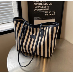 Detailed view of striped canvas tote bag with dark blue straps on a metal table