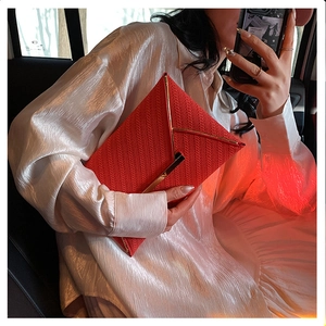 Détail de pochette enveloppe rouge avec texture tressée et bordure en métal doré