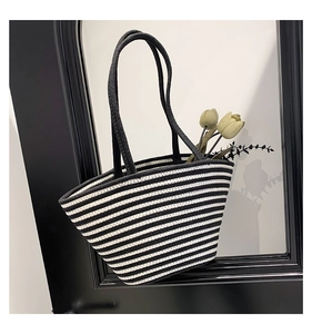 Détail du sac cabas tissé à rayures noires et blanches avec des bretelles cylindriques