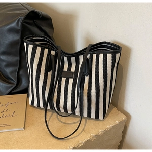 Detail of striped canvas tote bag with black leather trim and rectangular leather patch