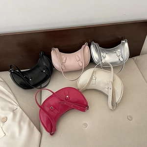 Modern crescent shoulder bags in five colors with adjustable straps on a beige sofa