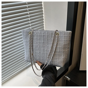 Zoom sur le sac cabas en tweed bleu clair avec des chaînes dorées élégantes et chic