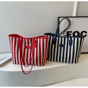Close-up of red and navy striped canvas tote bags with leather patches on display