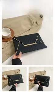 Détails d'une pochette enveloppe noire avec texture tissée et bordure en métal doré