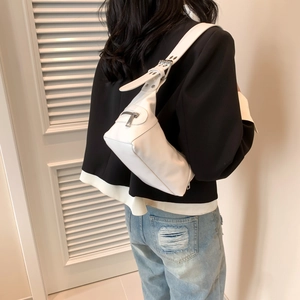 White leather shoulder bag with silver hardware worn by a model in a street style look