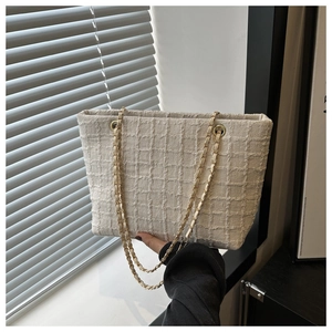 Détail du sac cabas en tweed blanc cassé montrant la texture et la chaîne dorée