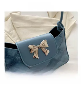 Detailed view of blue denim texture shoulder bag with silver metallic bow decoration
