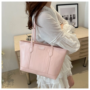 Dettaglio di una borsa tote rosa capiente in pelle martellata indossata da modella