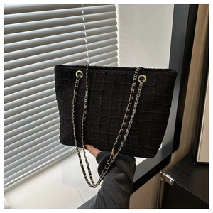 Gros plan du sac cabas en tweed noir avec motif quadrillé et chaîne dorée